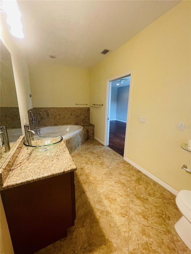 bathroom featuring tiled bath, toilet, vanity, and tile patterned floors