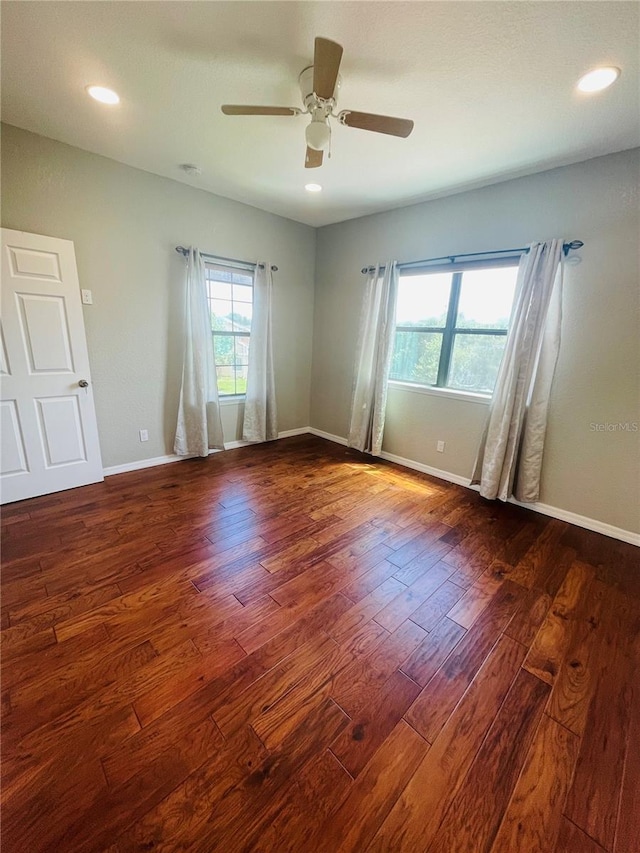 empty room featuring dark wood-type flooring, ceiling fan, and plenty of natural light