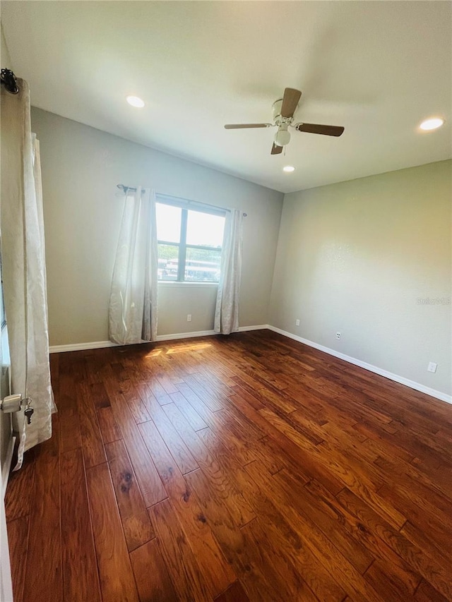 unfurnished room featuring dark wood-type flooring and ceiling fan