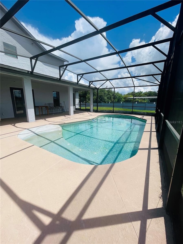 view of swimming pool with glass enclosure and a patio