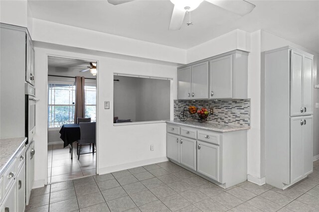 kitchen with gray cabinetry, oven, decorative backsplash, and light tile patterned floors