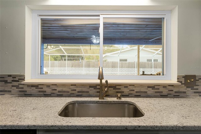 interior details with tasteful backsplash, light stone countertops, and sink