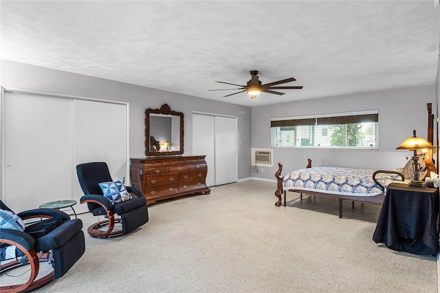 bedroom with two closets, ceiling fan, and a wall mounted air conditioner