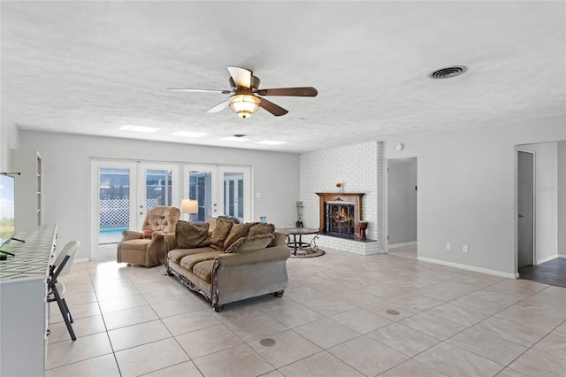 living room featuring a fireplace, light tile patterned floors, a textured ceiling, and ceiling fan