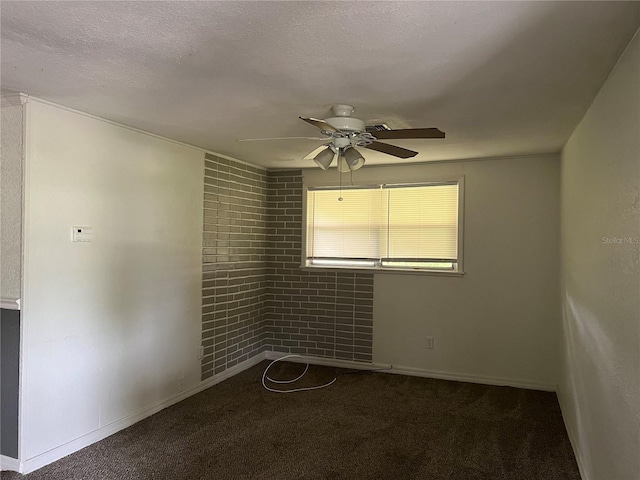 carpeted empty room with ceiling fan, brick wall, and a textured ceiling