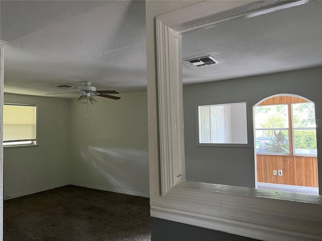 interior space with dark colored carpet, ceiling fan, and a textured ceiling