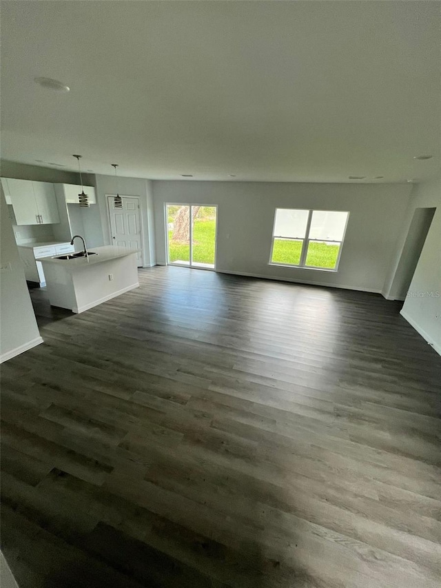 unfurnished living room with dark hardwood / wood-style flooring and sink