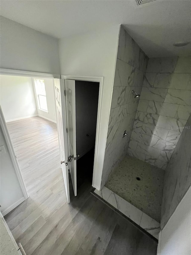 bathroom featuring hardwood / wood-style floors and a tile shower