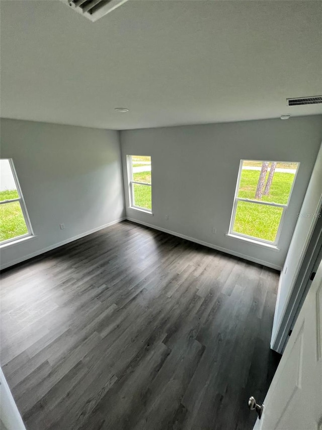 spare room with dark hardwood / wood-style flooring and a healthy amount of sunlight