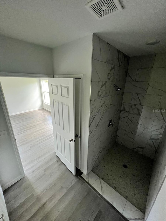 bathroom featuring a textured ceiling, a tile shower, and hardwood / wood-style floors