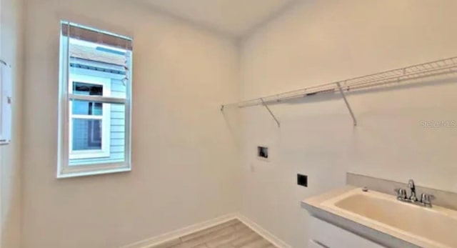 washroom featuring light wood-type flooring, sink, and hookup for an electric dryer