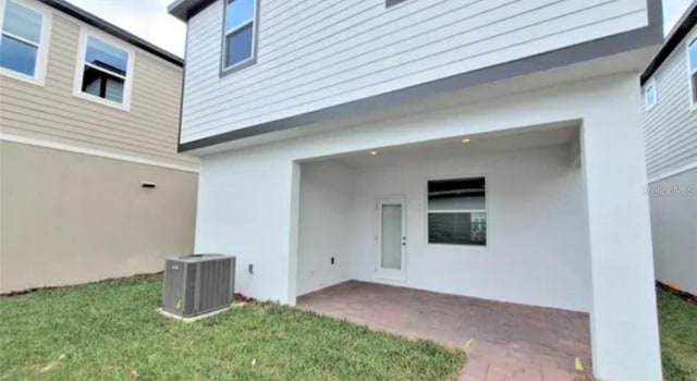 back of property featuring central air condition unit, a yard, and a patio area