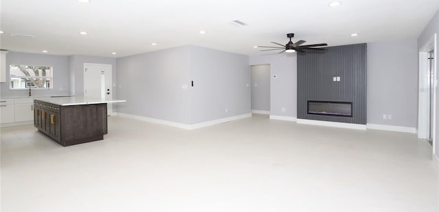 unfurnished living room with ceiling fan and a large fireplace