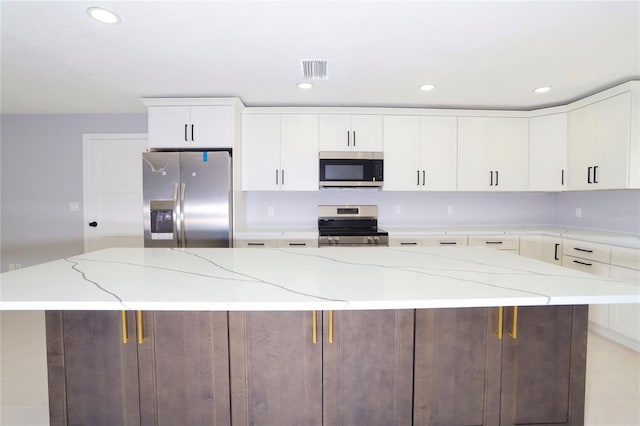 kitchen featuring appliances with stainless steel finishes, light stone countertops, white cabinetry, and a large island