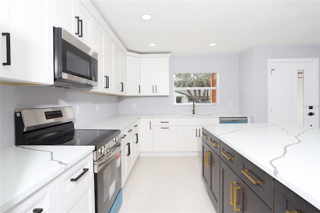 kitchen with stainless steel appliances, white cabinets, light stone counters, and sink