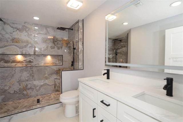 bathroom featuring vanity, tile patterned floors, toilet, and tiled shower