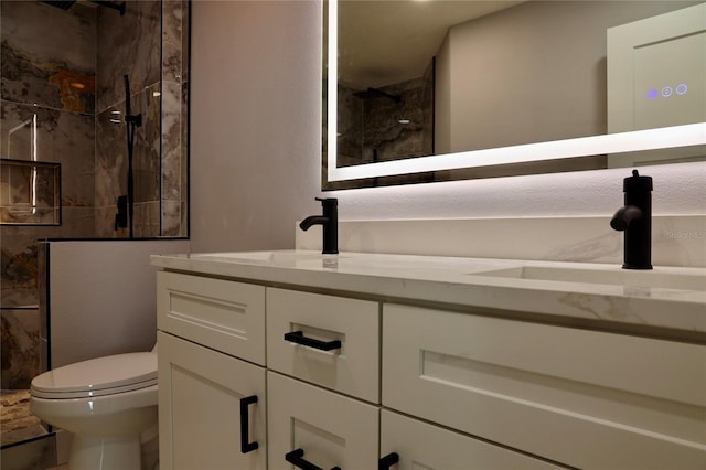 bathroom with a tile shower, vanity, and toilet