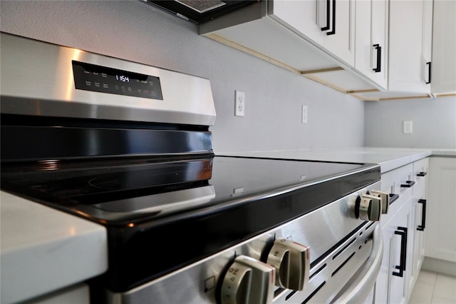 details featuring white cabinets, electric stove, and light tile patterned flooring