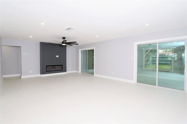 unfurnished living room with a large fireplace and ceiling fan