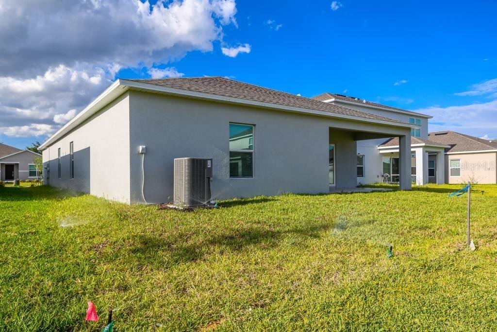 back of house featuring central AC and a yard