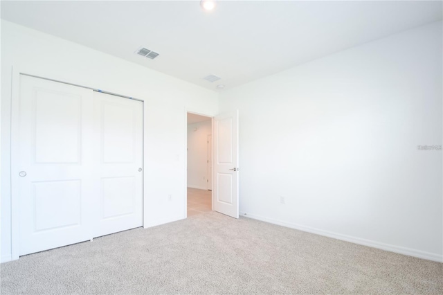 unfurnished bedroom featuring light carpet and a closet