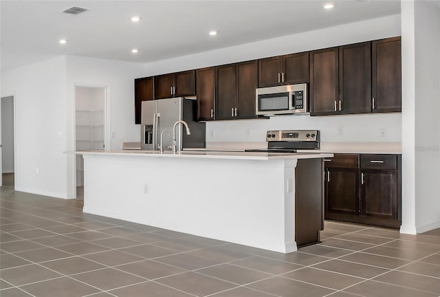 kitchen featuring sink, tile patterned flooring, a kitchen island with sink, stainless steel appliances, and dark brown cabinets