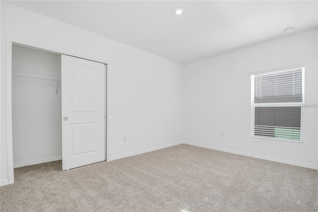 unfurnished bedroom featuring light colored carpet and a closet