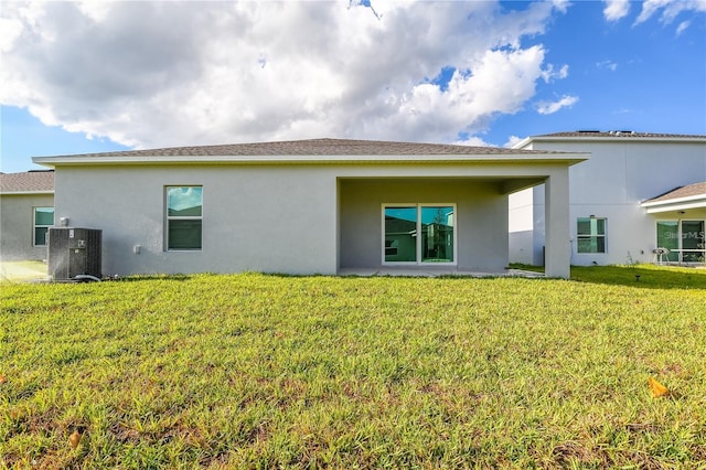 back of house featuring central AC unit and a lawn