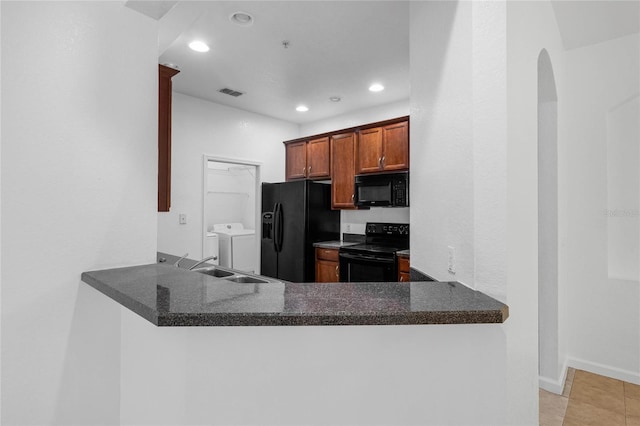 kitchen featuring light tile patterned flooring, independent washer and dryer, kitchen peninsula, black appliances, and sink