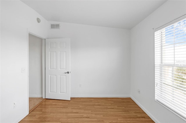 empty room featuring light hardwood / wood-style flooring and vaulted ceiling