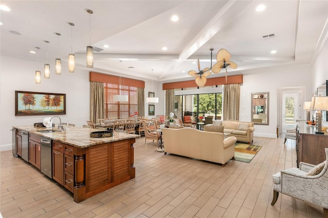 kitchen with a kitchen island with sink, plenty of natural light, pendant lighting, and light stone counters