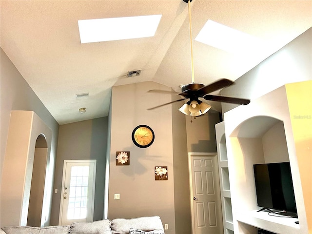 interior space featuring ceiling fan, a textured ceiling, and vaulted ceiling with skylight