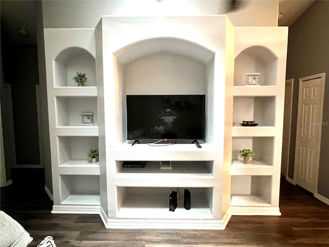 living room with built in shelves and dark wood-type flooring