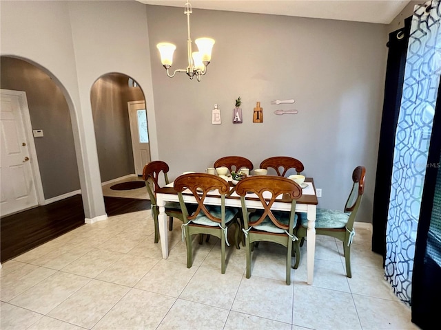 dining space with a notable chandelier, vaulted ceiling, and light tile patterned floors