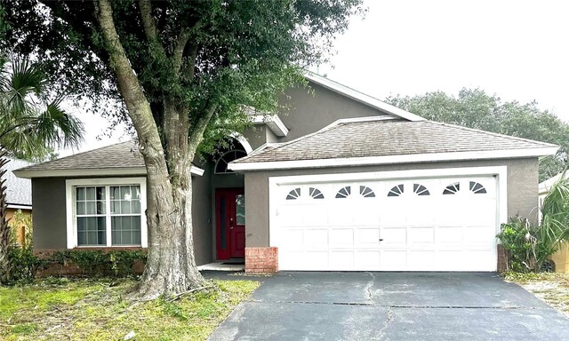 2556 Bear Creek Ct, Kissimmee, FL 34747 - view of front of house with asphalt driveway, a garage, stucco siding, and roof with shingles