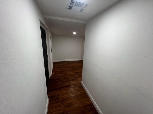 corridor featuring visible vents, baseboards, and dark wood-style flooring