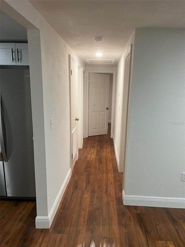 corridor with baseboards and dark wood-type flooring