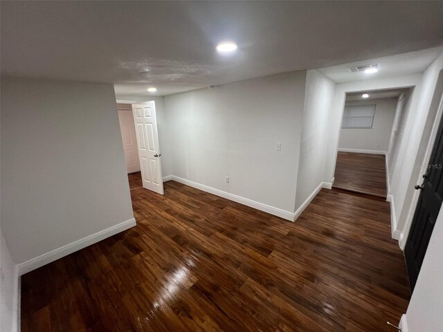 finished basement featuring visible vents, baseboards, and dark wood-style floors