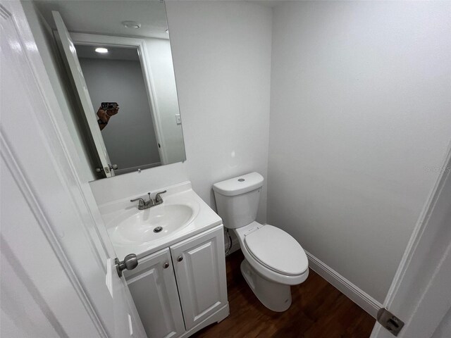 bathroom featuring wood-type flooring, vanity, and toilet