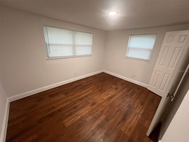 unfurnished bedroom with baseboards and dark wood-style floors