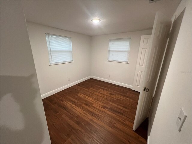 empty room featuring baseboards and dark wood-style flooring