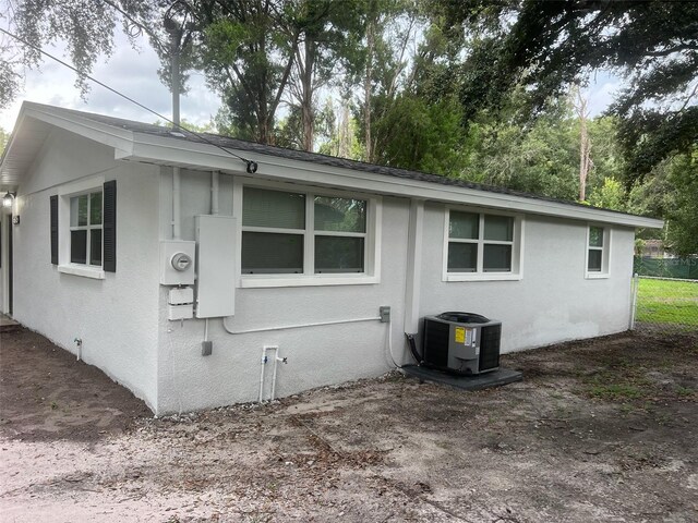 view of property exterior featuring stucco siding, central AC unit, and fence