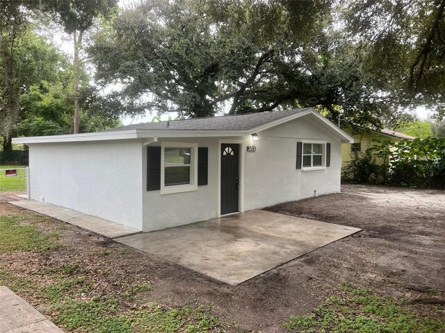 single story home with a patio area, roof with shingles, and stucco siding