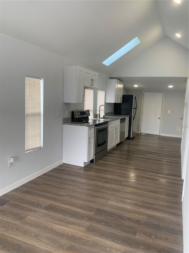 kitchen featuring appliances with stainless steel finishes, vaulted ceiling with skylight, dark hardwood / wood-style flooring, and white cabinetry