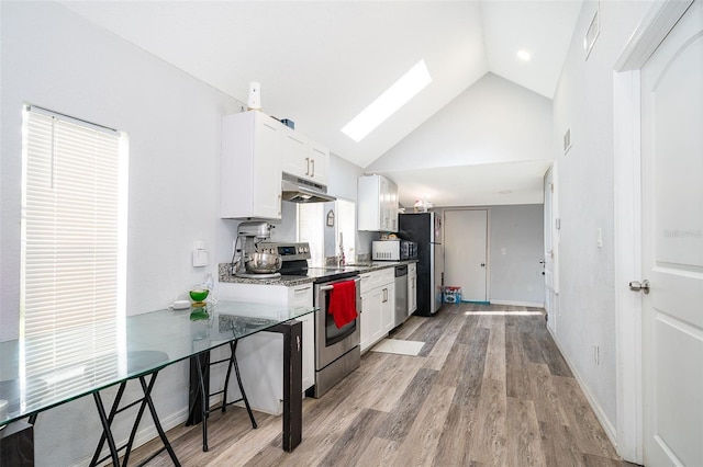 kitchen featuring dark stone countertops, white cabinetry, a skylight, light hardwood / wood-style flooring, and appliances with stainless steel finishes