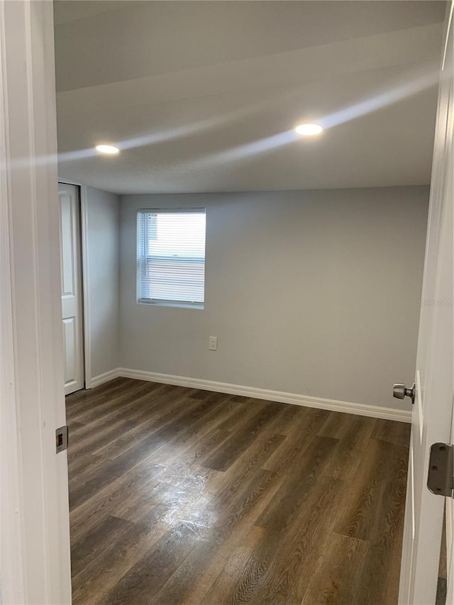 empty room with dark wood finished floors and baseboards