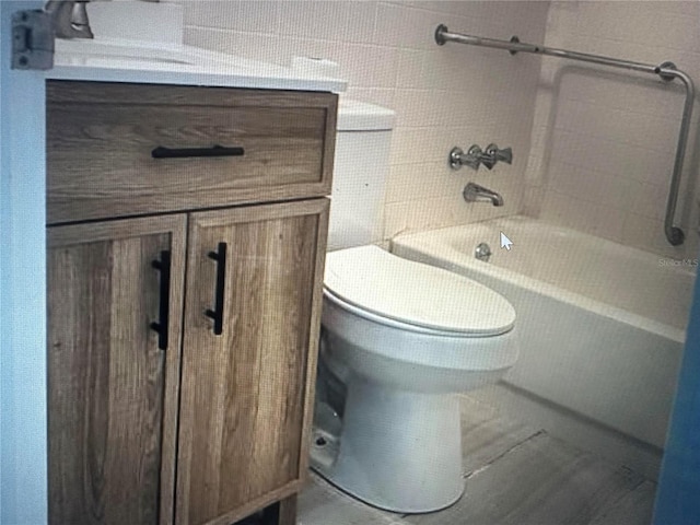 full bathroom with tiled shower / bath, vanity, toilet, and tile walls