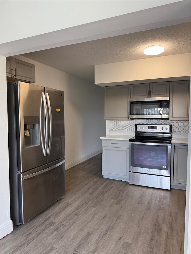 2070 World Parkway Blvd Unit 50, Clearwater, FL 33763 - kitchen with appliances with stainless steel finishes, gray cabinetry, light wood finished floors, and decorative backsplash