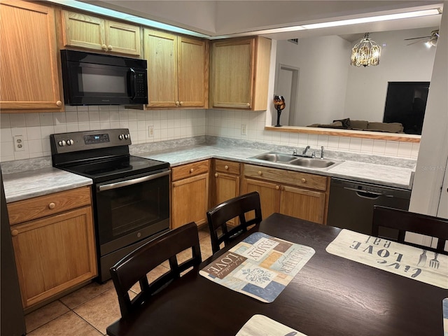 kitchen featuring tasteful backsplash, black appliances, an inviting chandelier, sink, and light tile patterned flooring