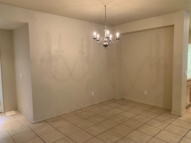 spare room featuring light tile patterned floors and a notable chandelier